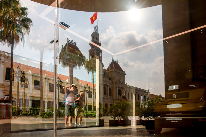 انعكاس مبنى اللجنة الشعبية لمدينة هو تشي منه على زجاج معرض سيارات "رولز رويس"