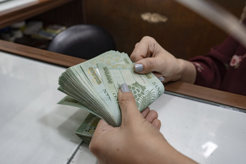 موظفة تعدّ الأوراق النقدية من فئة 100 ألف ليرة لبنانية في محل لصرف العملات بمنطقة برج حمود في بيروت، لبنان