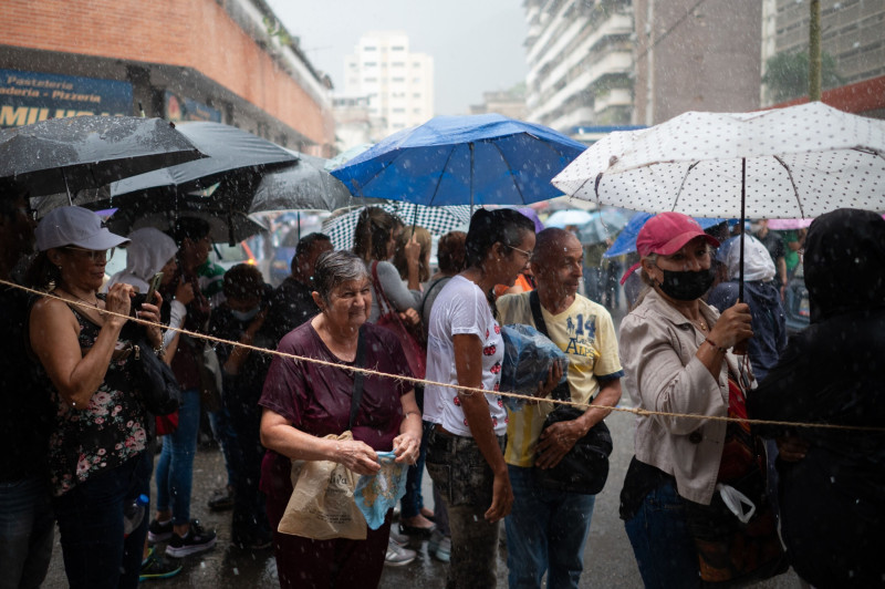 ناخبون ينتظرون في طابور تحت الأمطار الغزيرة للإدلاء بأصواتهم خارج مركز اقتراع خلال الانتخابات التمهيدية للمعارضة في كراكاس 