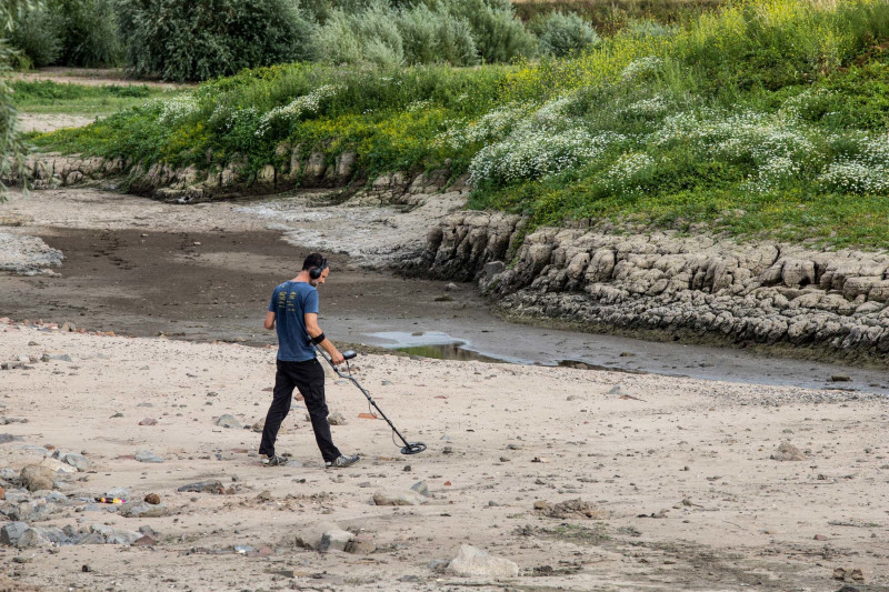 رجل يبحث في القاع المكشوف لنهر الراين باستخدام كاشف معادن في لوبيث، هولندا بتاريخ 30 يوليو.