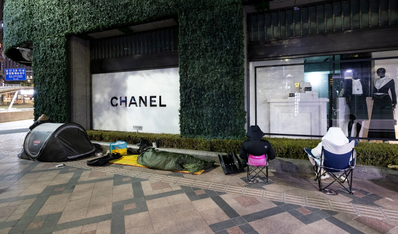 متسوقون ينتظرون أمام متجر "شانيل" في سيؤول، كوريا الجنوبية، بعضهم داخل الخيم أو على كراس محمولة