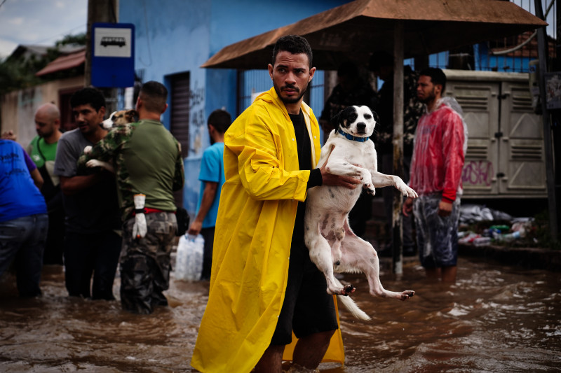 أحد السكان يحمل كلباً وسط مياه الفيضانات بمدينة كانواس، في ولاية ريو دي غراند دو سول، البرازيل