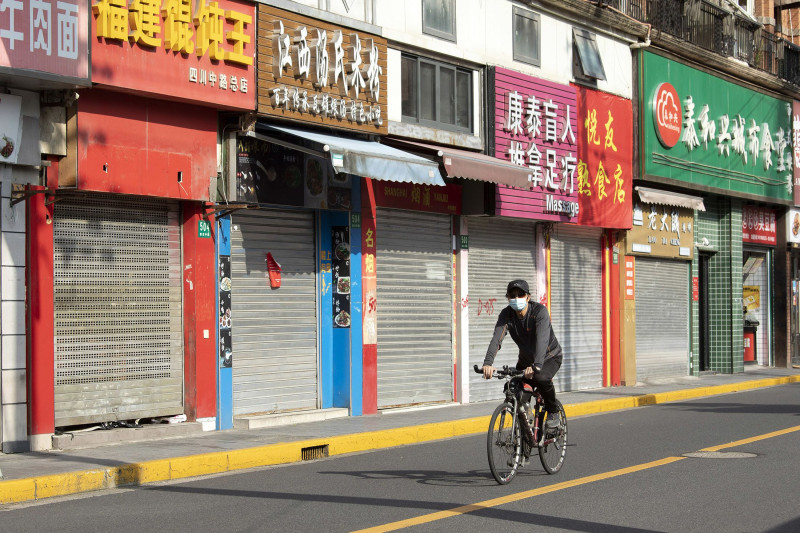 رجل يمر بدراجته قرب متاجر مغلقة في شنغهاي إبان الإغلاق درءاً لتفشي الوباء 
