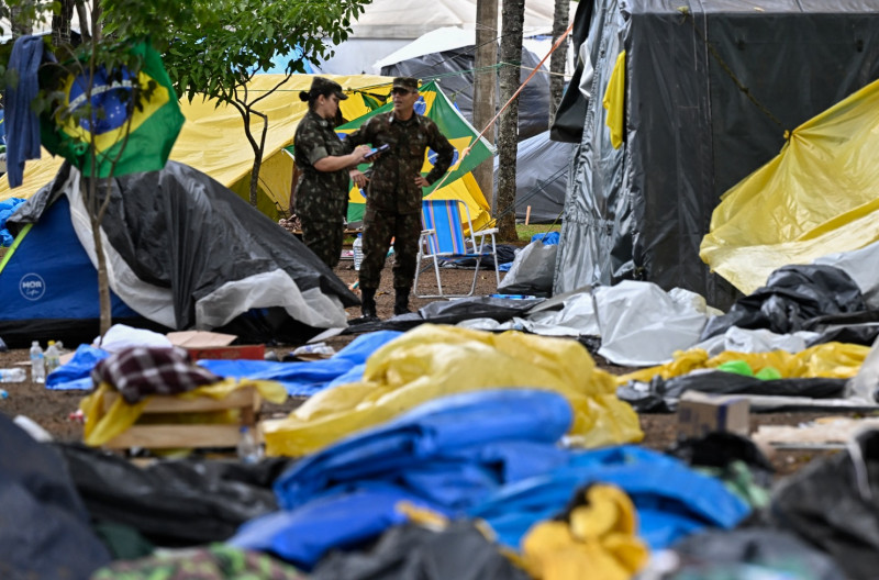 عنصران من قوات الأمن أثناء تفكيك الخيم التي نصبها أنصار الرئيس البرازيلي السابق جايير بولسونارو أمام المقر العسكري في برازيليا، يوم 9 يناير 2009.