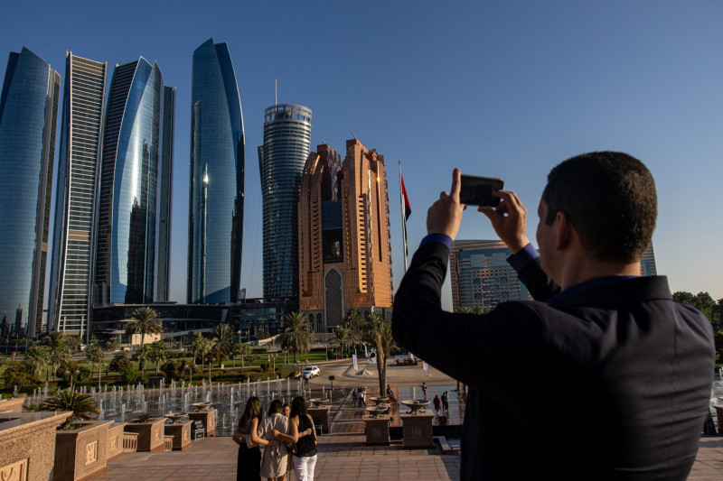 زائر يستخدم هاتفاً ذكياً لالتقاط صورة لأبراج الاتحاد في أبوظبي، الإمارات، يوم 24 نوفمبر 2022