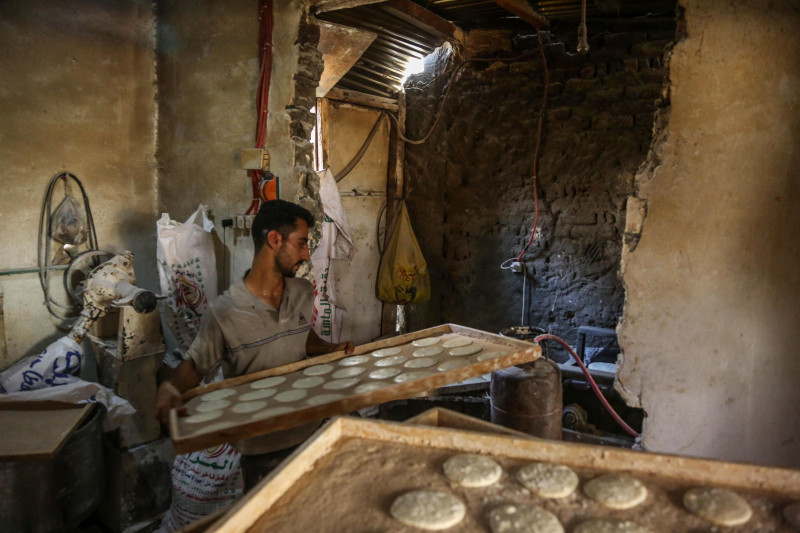 عامل يُعِدّ عجينة لطهي الخبز البلدي التقليدي داخل مخبز في منطقة الجعفرية بمركز السنطة