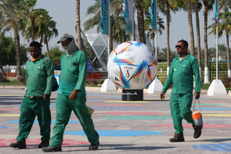 عمال يمرون بالقرب من نموذج لكرة "أديداس" الرسمية لكأس العالم 2022 "الرحلة"، الدوحة، قطر