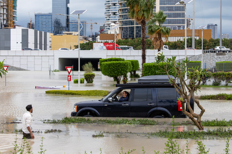 سائق يحاول التنقل في أحد الشوارع المغمورة في المياه في مدينة دبي الرياضية