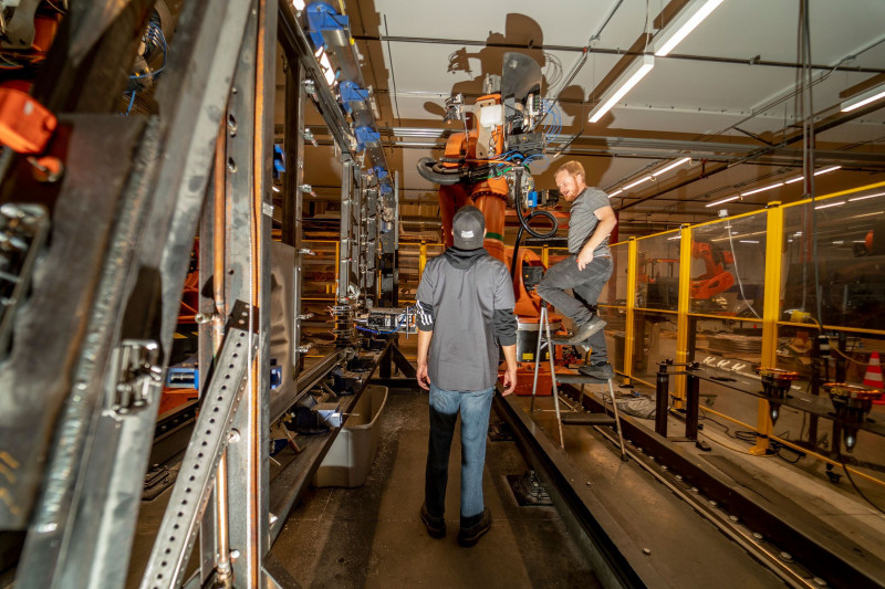 عمال في مصنع "ماشينا" يضبطون إعدادات روبوت.