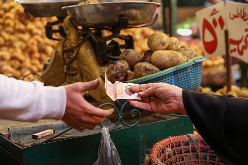 سيدة تسلّم بائعاً ثمن مشترياتها من الخضار في سوق المنيرة للأغذية في حي إمبابة بالجيزة، مصر، في 7 يناير 2023