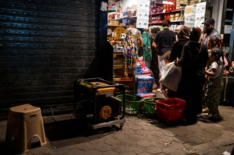 عملاء ينتظرون في طابور أمام أحد المتاجر أثناء انقطاع التيار الكهربائي بسبب سياسة تخفيف الأحمال، حي السيدة زينب، القاهرة، مصر