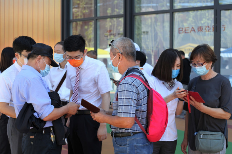 المضيفون في جناح "بنك أوف تشاينا" يساعدون المقيمين على إنشاء حسابات باليوان الرقمي على هواتفهم