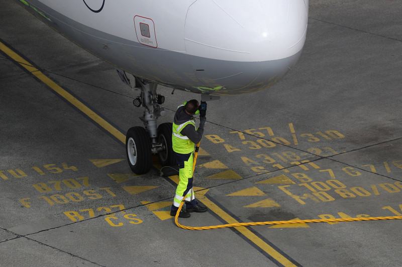 أحد أفراد طاقم الخدمات الأرضية يربط وصلة الوقود بطائرة إيرباص.