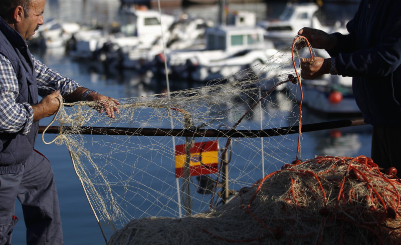 صيادان يحملان شبكة صيد في ميناء باربات في باربات، الساحل الجنوبي لإسبانيا