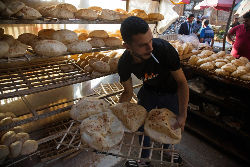 عامل يرتب خبزاً طازجاً للبيع في سوق المنيرة في القاهرة، مصر، 1 يونيو 2022. 