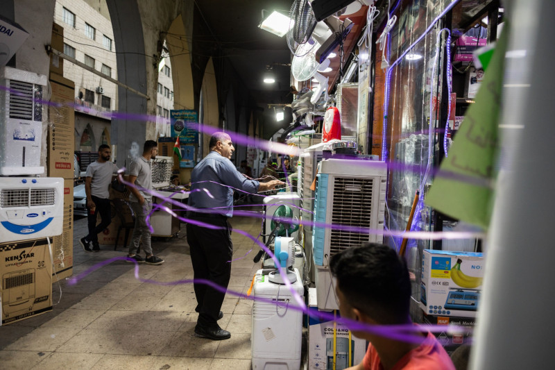 رجل يقف أمام متجر لبيع المراوح الهوائية، الأردن